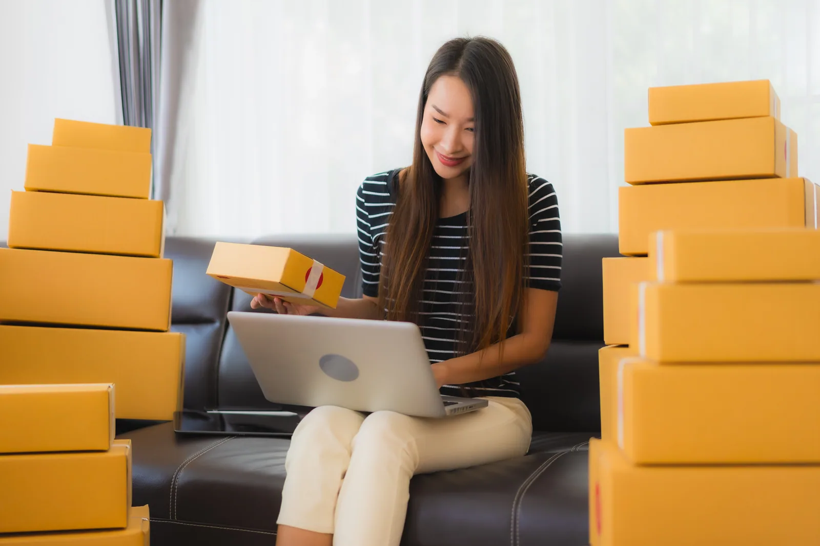 An ecommerce operator working on a laptop among outgoing packages