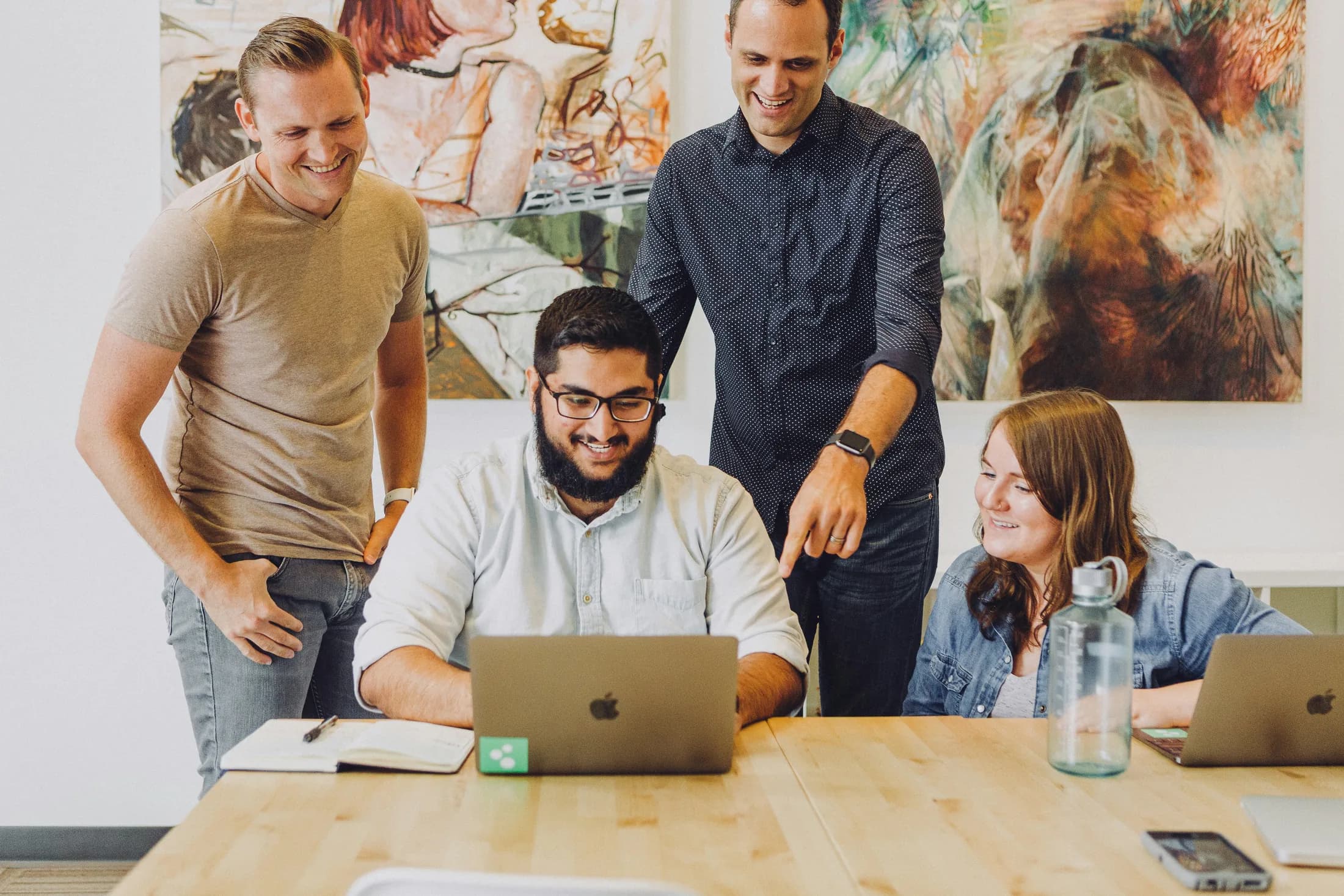A small team reviewing work together on a laptop