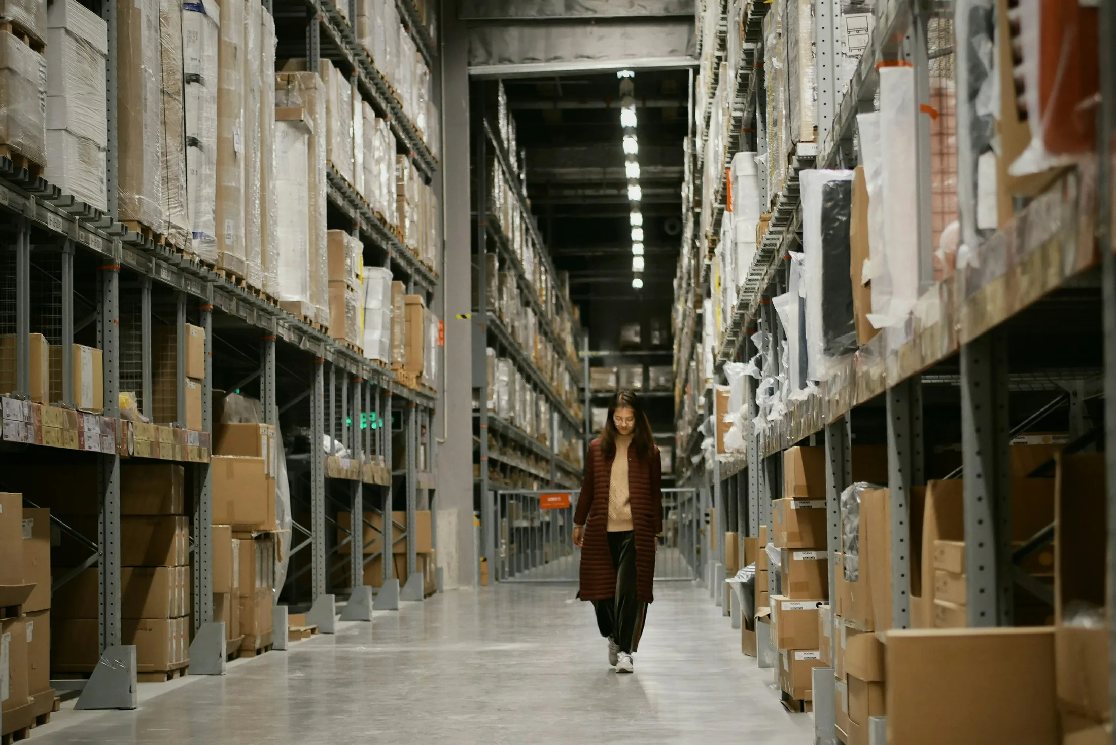 An operations lead walking through an active warehouse aisle
